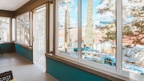 A room with large windows, a view of the street, and a chair.