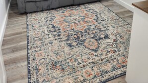 A gray reclining sofa in a room with a patterned rug and a window. - Ninth Door Mention Apt 13 Main St. Milbridge (Milbridge)