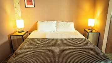 Una habitación de hotel con una cama, dos lámparas de noche y un cuadro en la pared.