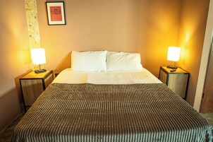 Una habitación de hotel con una cama, dos lámparas de noche y un cuadro en la pared.