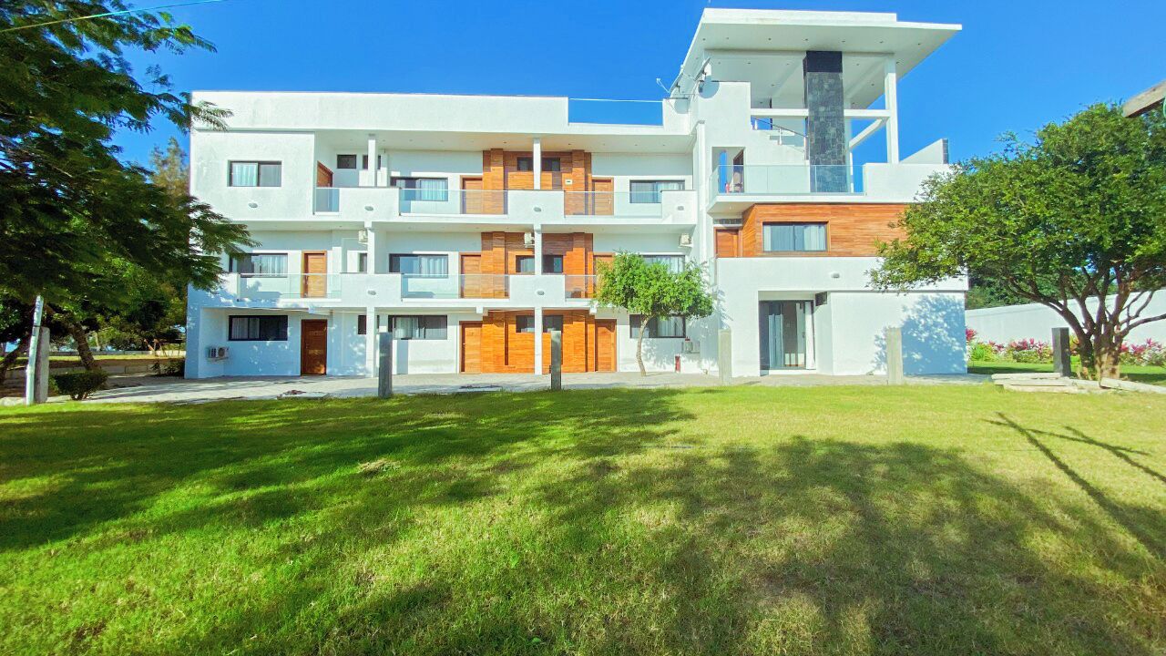 Un edificio moderno de varios pisos con techo plano, ventanas amplias y un césped bien cuidado.