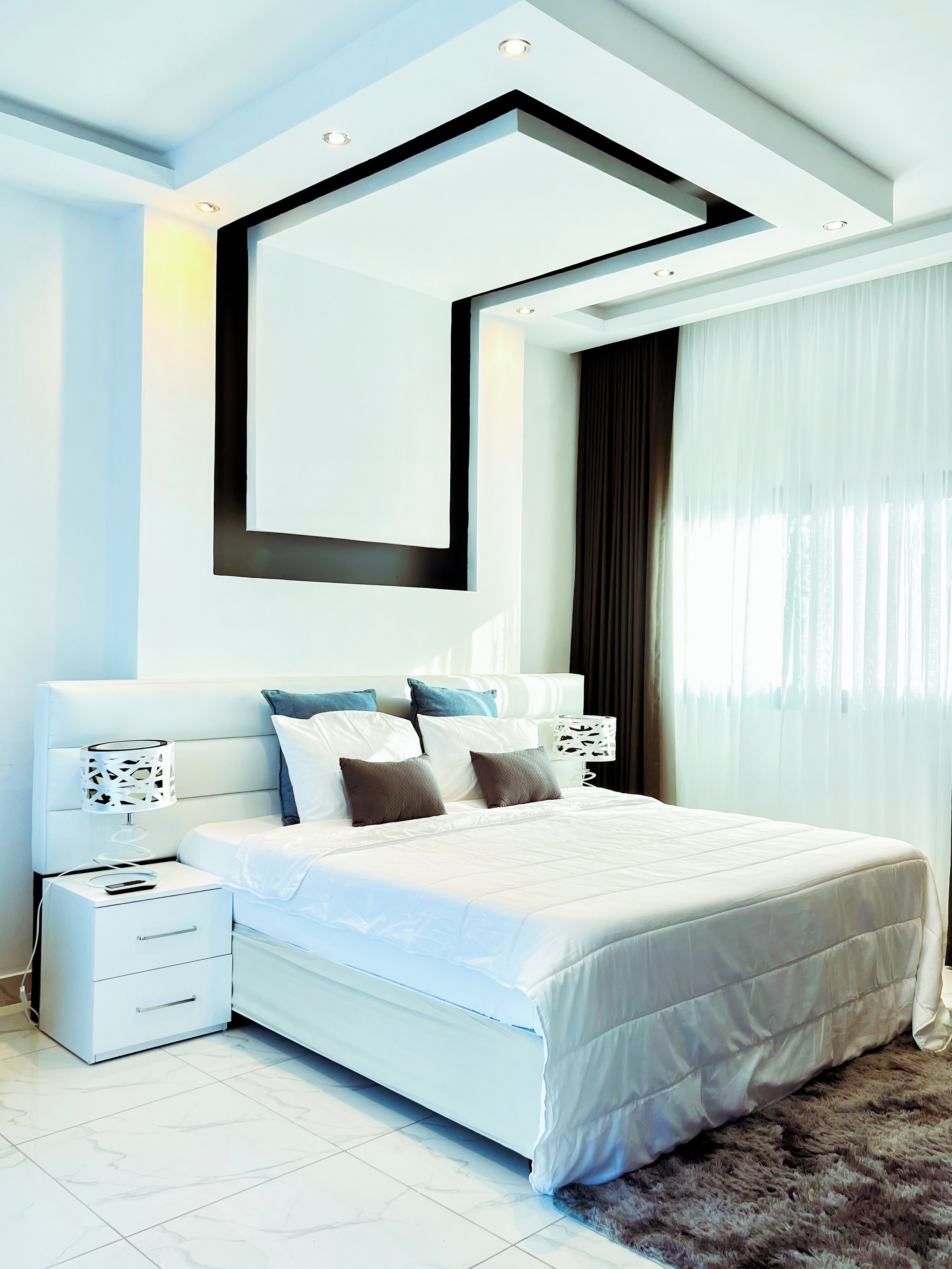 A modern bedroom with a large bed, bedside tables, a nightstand, and a large mirror.