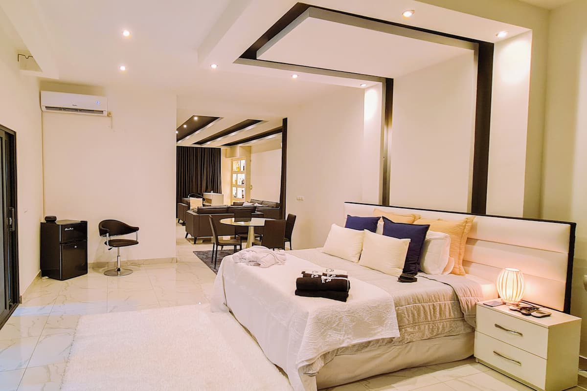 Una habitación de hotel moderna con una cama grande, un escritorio, una silla y un espejo.