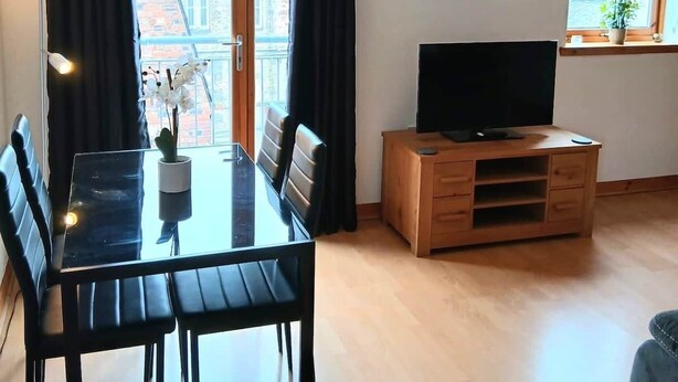 Ett modernt vardagsrum med ett matbord, stolar, en tv och ett fönster med gardiner.