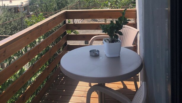 Un balcón con una mesa redonda, sillas y una planta en maceta.