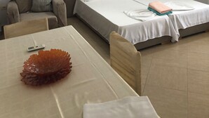 Una habitación de hotel con cama, sofá, mesa de comedor y ventilador de techo.