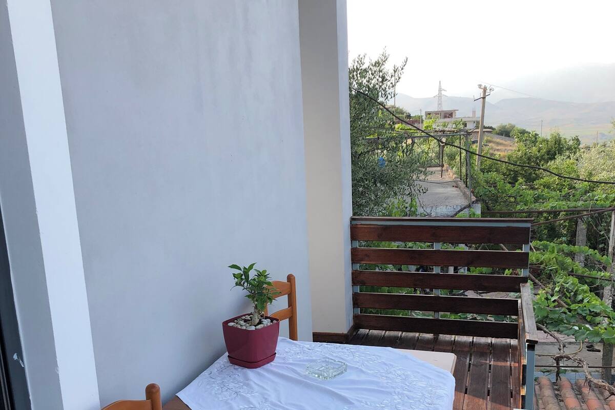 A balcony with a table, chairs, and a potted plant.