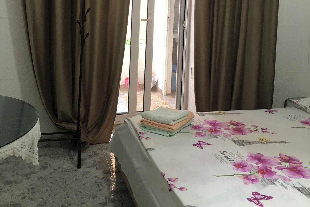 A room with a bed, a table, and a curtain rod.
