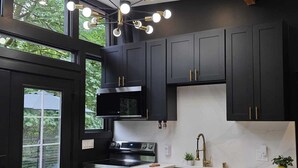 Une cuisine moderne avec des meubles de couleur sombre, des appareils électroménagers en acier inoxydable et un puits de lumière.