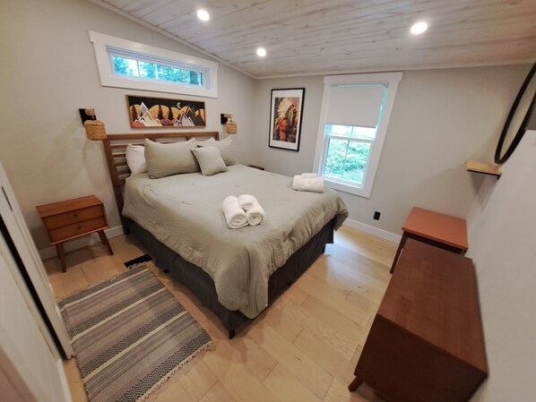 A bedroom with a bed, bedside tables, a window, and artwork on the walls.