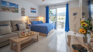 A hotel room with a bed, a sofa, a coffee table, and a balcony with a view. - Echeide: A cozy retreat in Costa Adeje with breathtaking views (Costa Adeje)