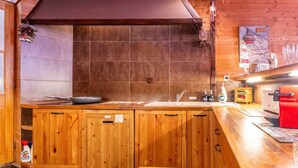 A kitchen with wooden cabinets, a sink, and a red coffee machine. - Holiday home 6 bedrooms, pool table, sauna, and foosbal (Le Mont-Dore)