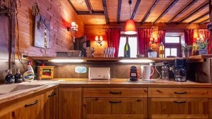 A wooden kitchen with a wooden countertop, a coffee maker, and a window with red curtains. - Holiday home 6 bedrooms, pool table, sauna, and foosbal (Le Mont-Dore)