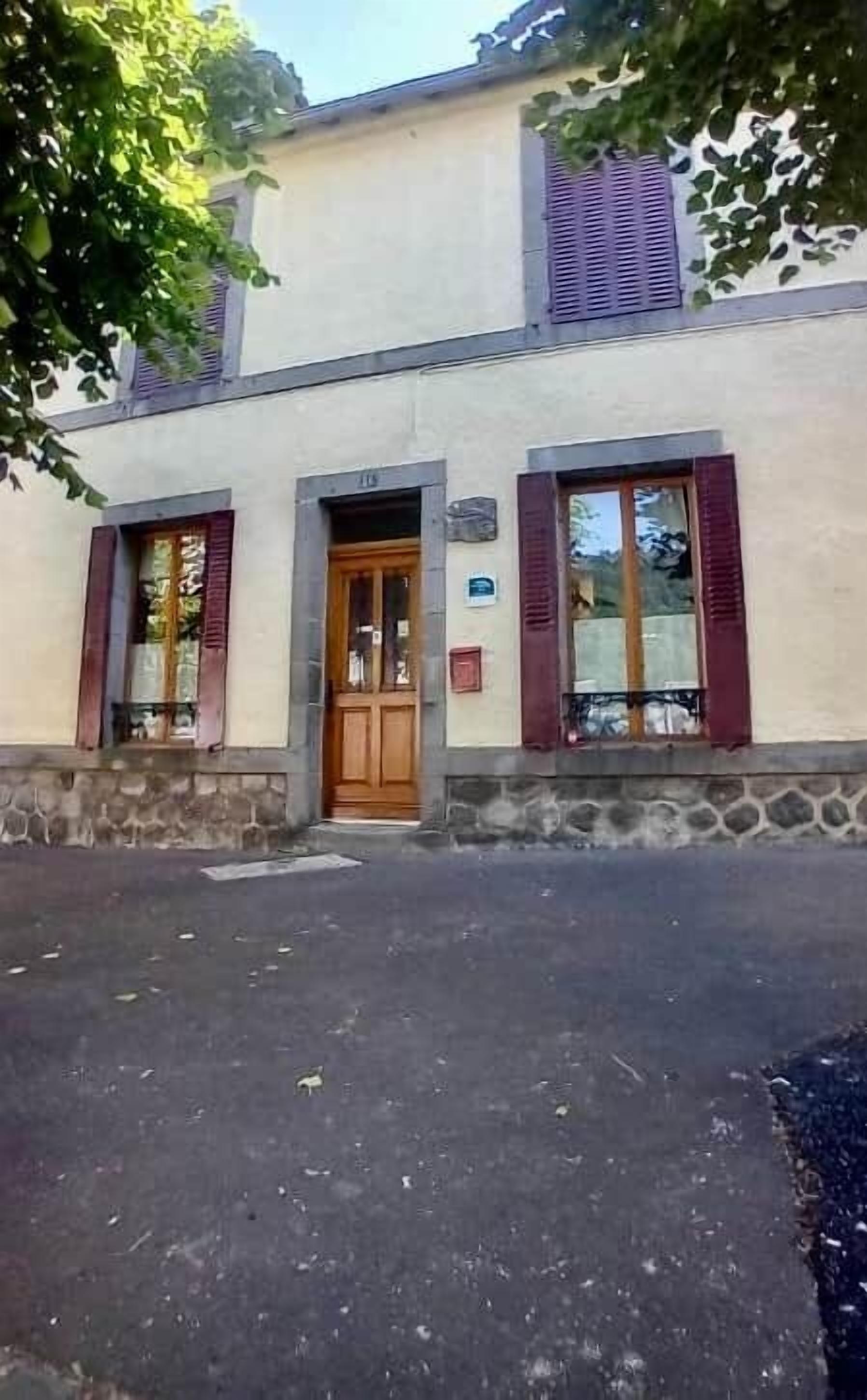 Ein Gebäude mit einer Holztür, zwei Fensterläden und einem Steinsockel.
