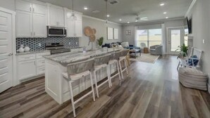 Una cocina moderna con gabinetes blancos, una isla de mármol y taburetes de bar.
