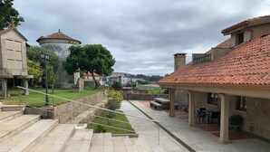 A stone staircase leading up to a building with a tiled roof, surrounded by greenery and a clear sky.