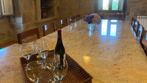 A stone-walled dining area with a long table, chairs, and a vase of flowers.