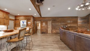 Une cuisine spacieuse aux murs en bois, un coin repas avec des chaises et un canapé.