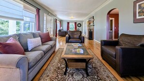 A spacious living room with a grey sofa, a brown leather armchair, and a coffee table. - Historic Vineyard Escape, with patio and vintage charm-Pet friendly! (Dayton)