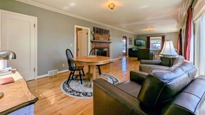 A living room with a fireplace, a dining table with chairs, a black leather sofa, and a lamp. - Historic Vineyard Escape, with patio and vintage charm-Pet friendly! (Dayton)