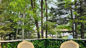 Una terraza de madera con sillas de mimbre y una pequeña mesa.