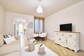 Una sala moderna con un sofá, una mesa de comedor y un televisor sobre un mueble.