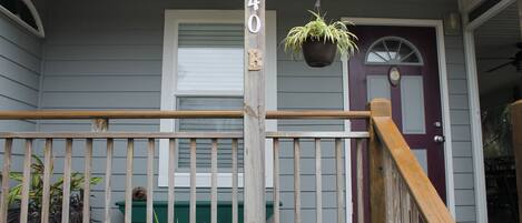 A porch with a wooden railing, a green bench, and a hanging plant.