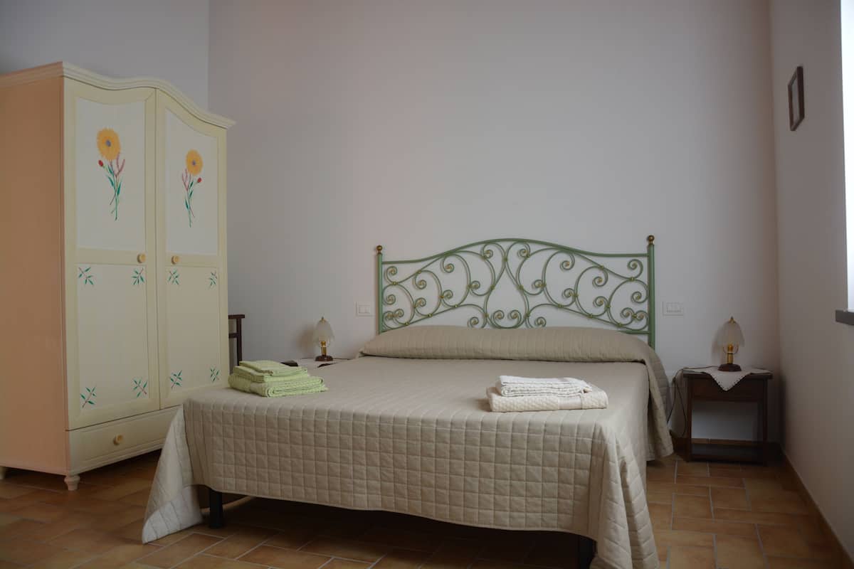 Une chambre à coucher comprenant un lit, une armoire, deux tables de chevet et un luminaire fixé au mur.