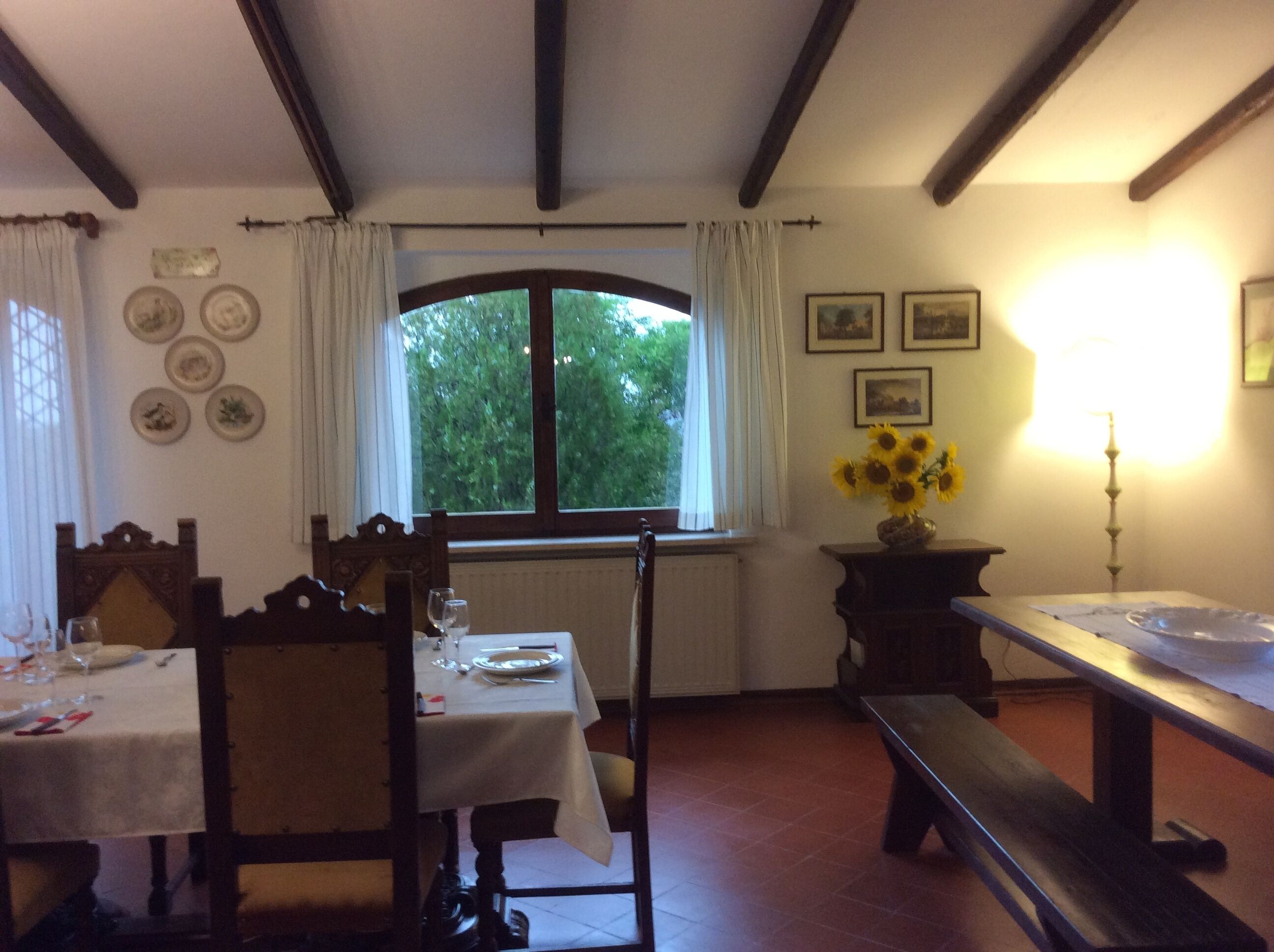 Zona pranzo con tavolo per due persone, una panca e una finestra con tende.