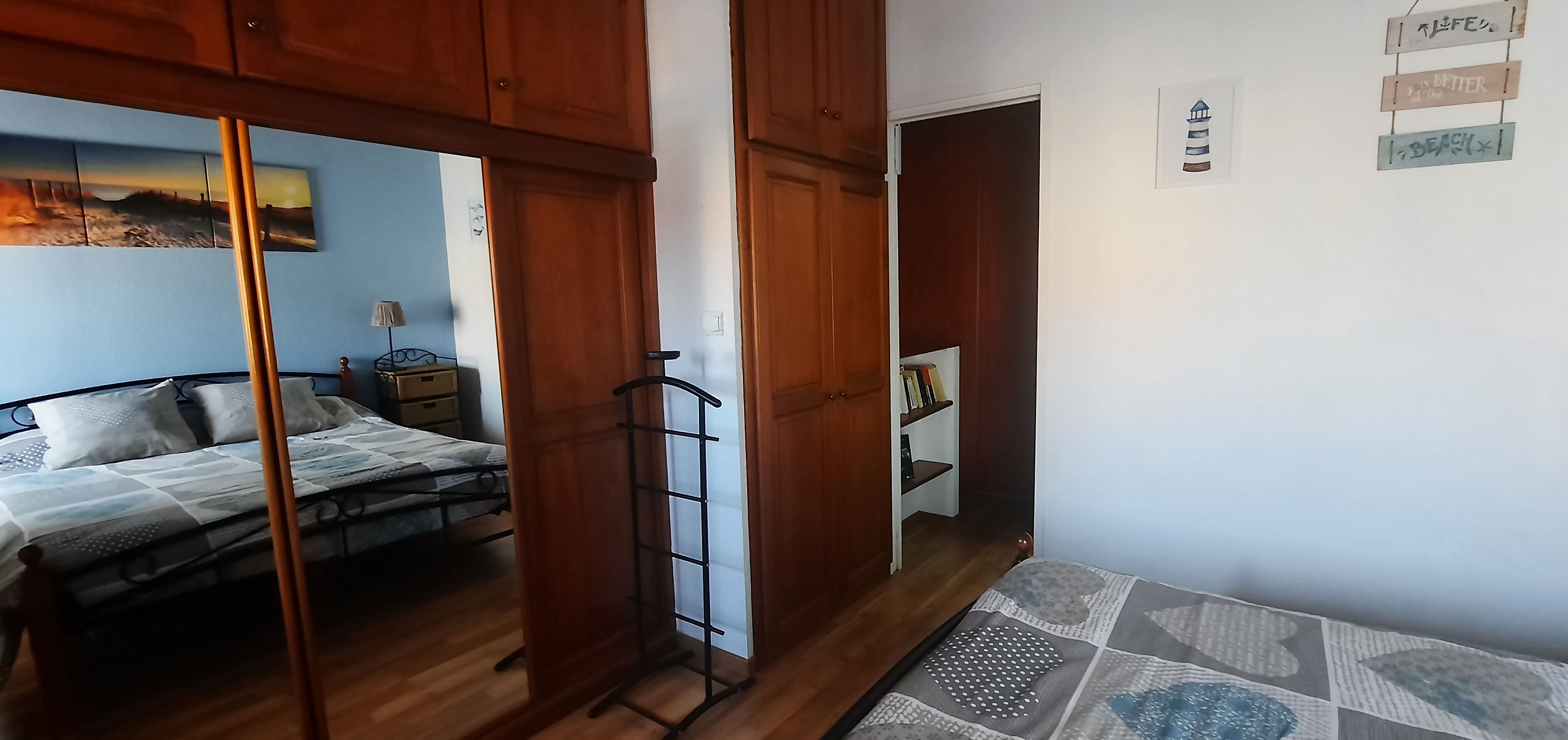 Ein Schlafzimmer mit einem Bett, einem Kleiderschrank und einem Regal mit Büchern.