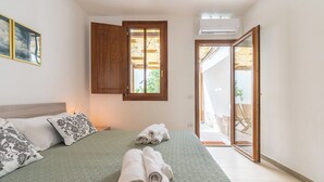 A bedroom with a bed, pillows, a window, and a door leading to a balcony. - La Casa dei Fiori d'Arancio (Capoterra)
