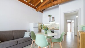 A modern kitchen with a dining area, featuring a sofa, dining table, and chairs. - La Casa dei Fiori d'Arancio (Capoterra)