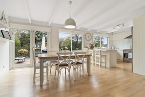 A spacious kitchen with a central island, wooden flooring, and large windows offering a view of the outdoors.