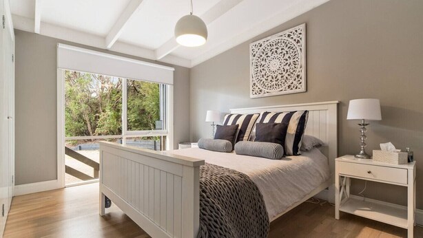 Een slaapkamer met een bed, nachtkastjes, een raam en uitzicht op het landschap.