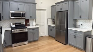 A modern kitchen with grey cabinets, stainless steel appliances, and a herringbone tile backsplash. - Welcome to your perfect getaway or family retreat in beautiful Magnolia Texas ! (Magnolia)