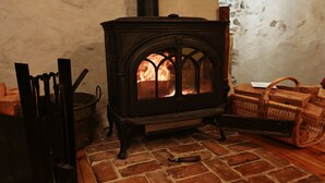 A wood-burning stove with a brick floor, a stone wall, and a basket of firewood. - Characteristic village house, sleeps 10 (Beauvezer)