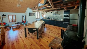 A spacious room with wooden floors, a dining table, and a kitchen area with modern appliances. - Characteristic village house, sleeps 10 (Beauvezer)