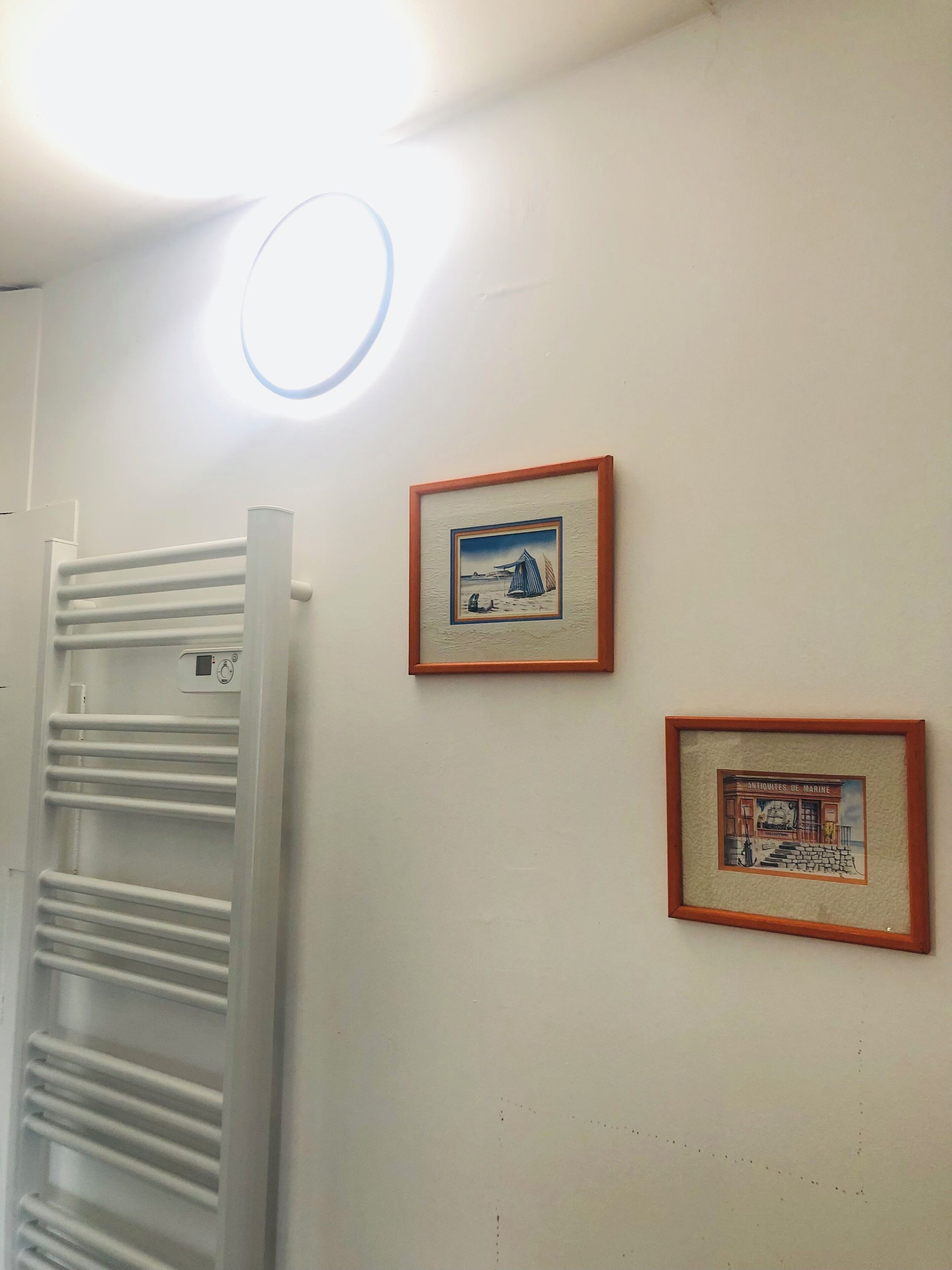 A white wall with two framed pictures and a white radiator.
