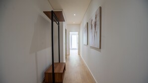 Un couloir avec un banc en bois, un porte-manteau en métal et une œuvre d’art encadrée accrochée au mur.