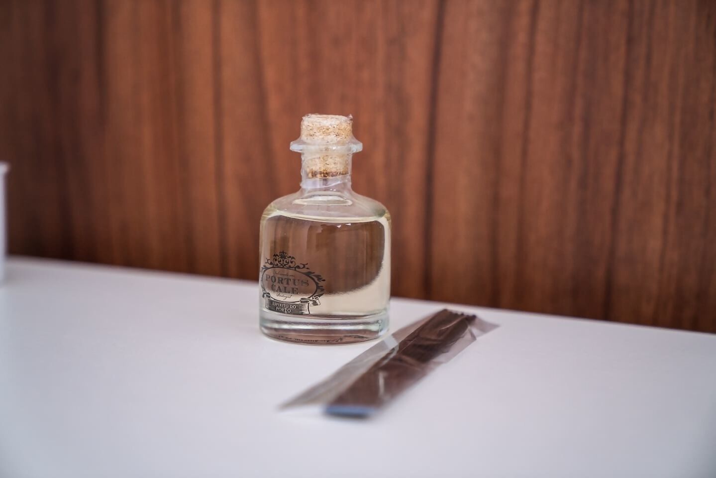 Een fles Portus Cale op een witte tafel met een houten achtergrond.