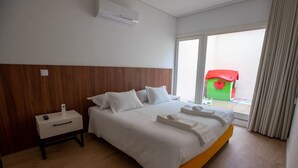Une chambre d’hôtel avec un lit, une table de chevet et une fenêtre donnant sur une maison de jeu verte.