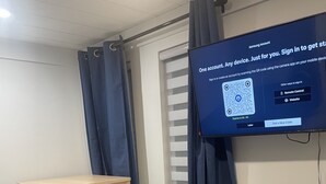 Un salon moderne avec un canapé, une petite table et un fauteuil. Un téléviseur à écran plat fixé au mur affiche l’écran de connexion au compte Samsung.