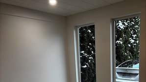 Une pièce avec deux fenêtres, des murs blancs et un sol carrelé.