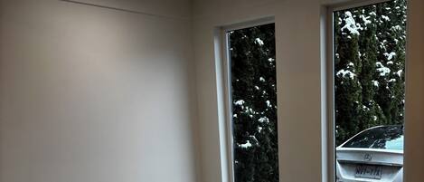 A room with two windows, white walls, and a tiled floor.