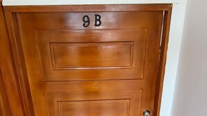 A wooden door with the number 9B, a keyhole, and a door handle.