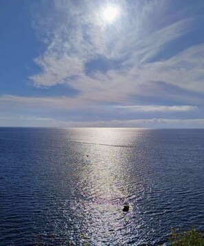 A calm sea with a clear sky and the sun reflecting on the water. - Apartment with lovely view, quiet, in city center. (Taormina)