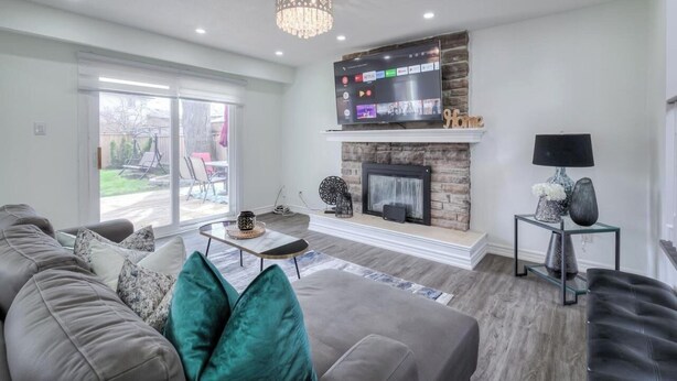 Een moderne woonkamer met een open haard, een flatscreen televisie erboven en een kroonluchter.