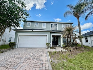 A two-story house with a garage, a paved driveway, and a well-maintained lawn.