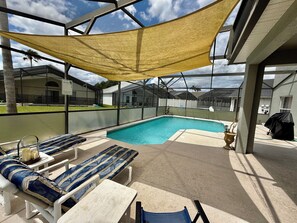 Uma área de piscina ao ar livre com espreguiçadeiras e um espaço de estar coberto.