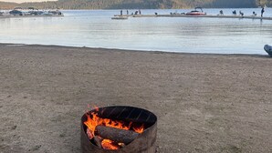 Una spiaggia con un braciere in primo piano e barche sull'acqua sullo sfondo.